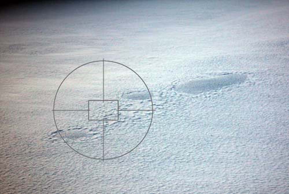A planetary surface covered with ice with a camera reticule showing possible landing site.