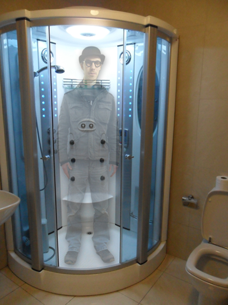 A young man in a shower cubicle fully dressed and wearing bowler hat is semi transparent.